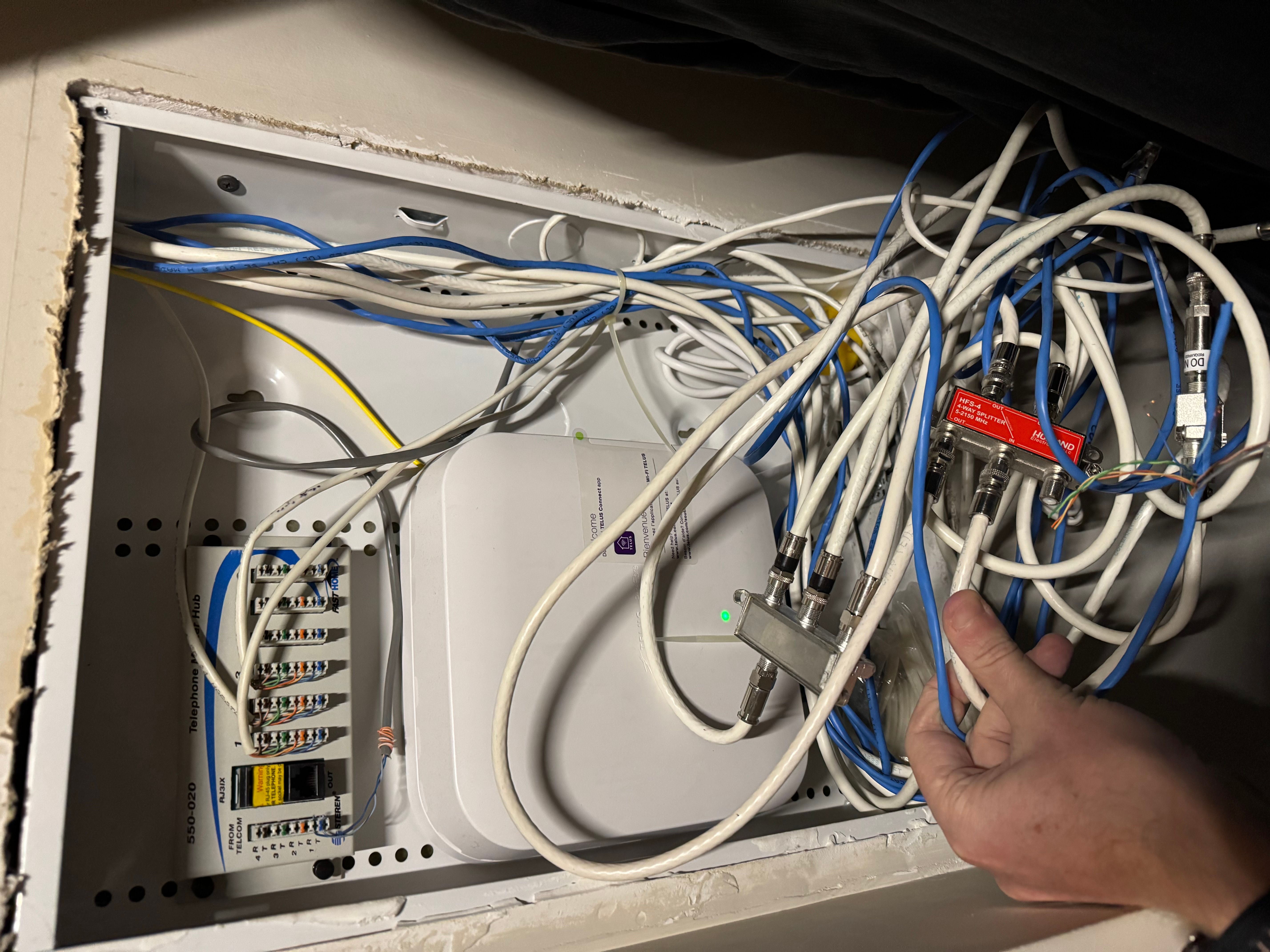 Mess of cables in cabinet with network access hub | TELUS Neighbourhood